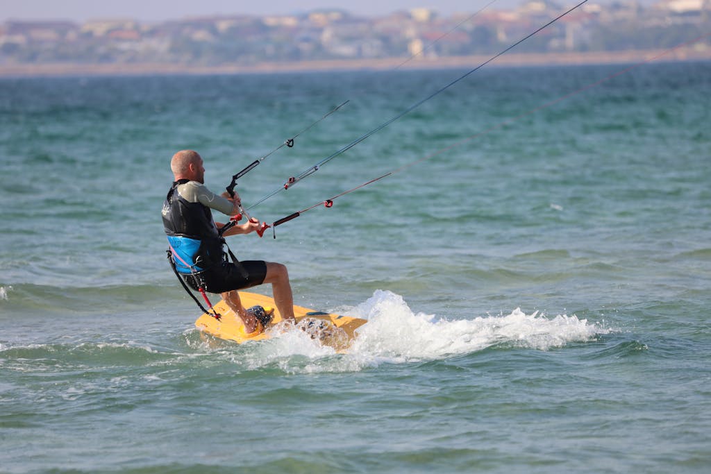 A man enjoying kitesurfing on a sunny day at the beach, showcasing thrilling water sports action.