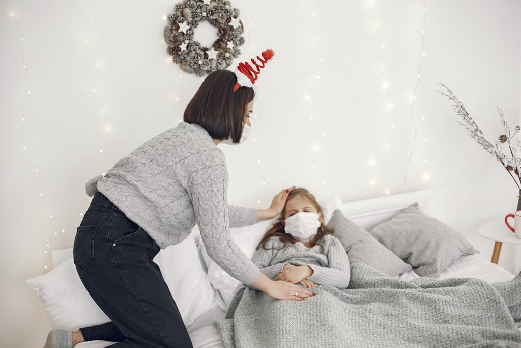 A mother comforts her daughter in bed with festive decor and face masks.