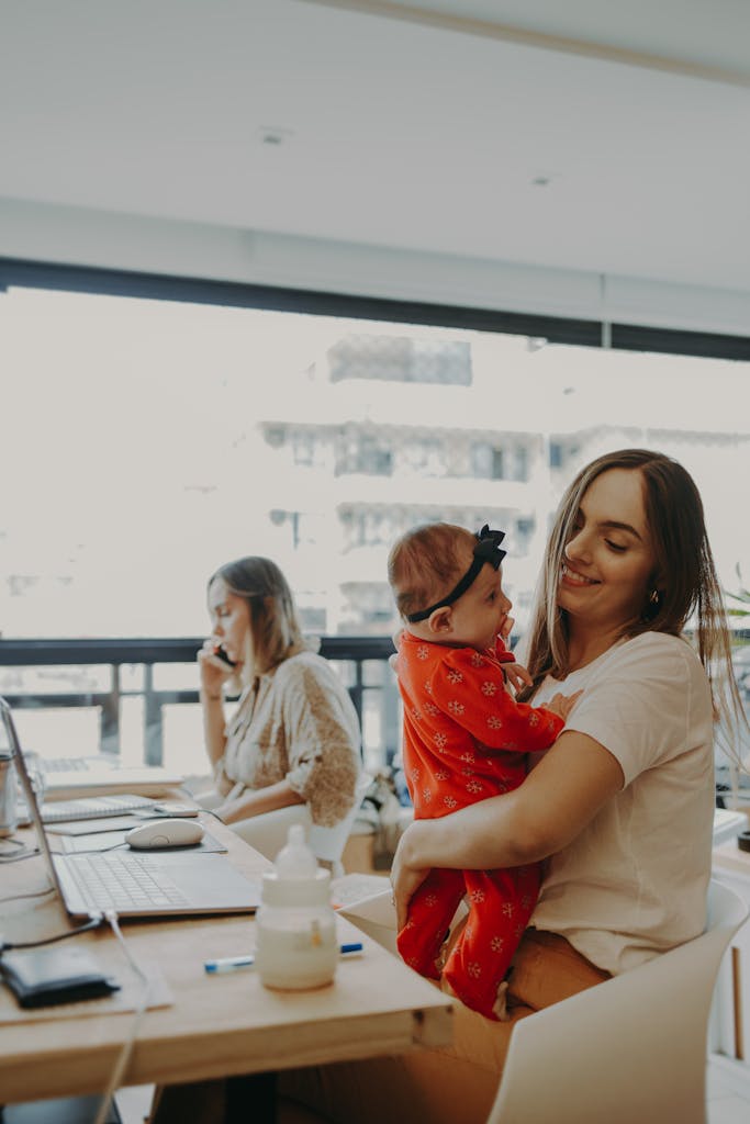 A mother holding her baby while working at a modern office, exemplifying work-life balance.