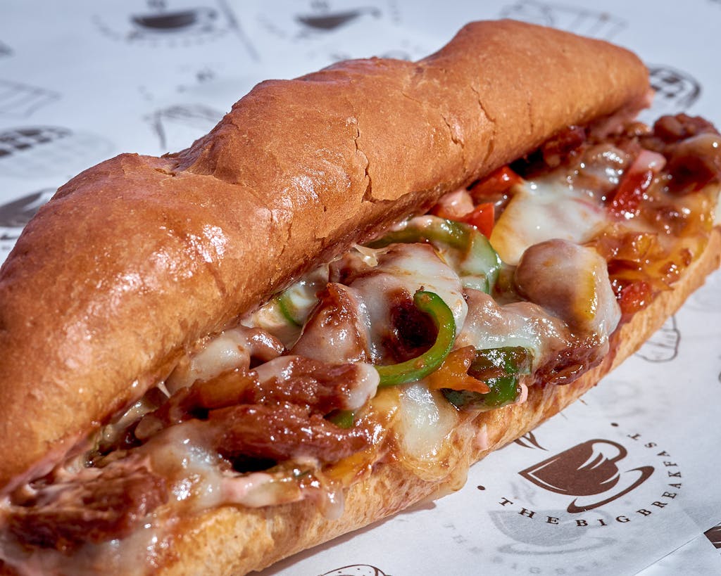 A mouthwatering close-up of a cheese steak sub with melted cheese, onions, peppers, and steak.