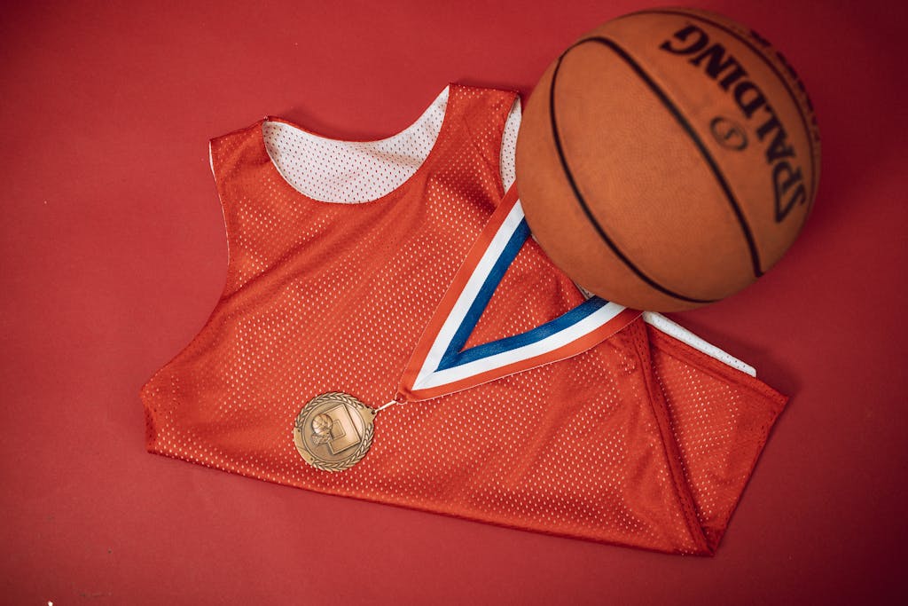 A red basketball jersey paired with a medal and Spalding basketball on a red backdrop.