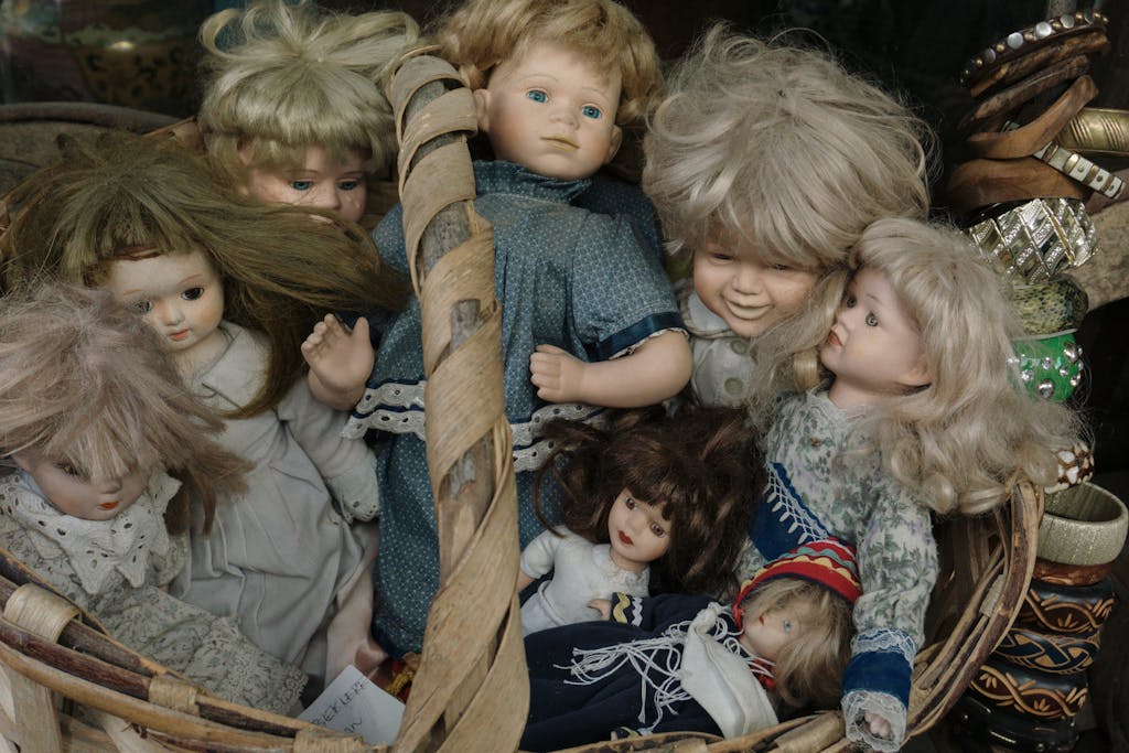A selection of vintage porcelain dolls in a woven basket. Ideal for collectors.