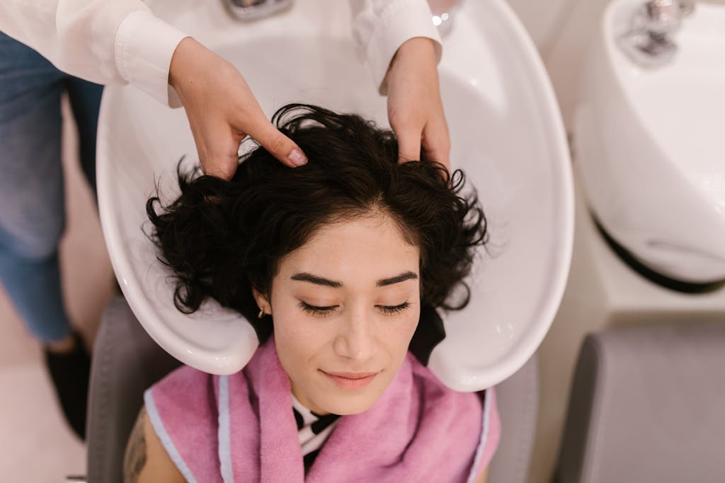 A serene woman enjoys a hair wash and massage at a contemporary hair salon.
