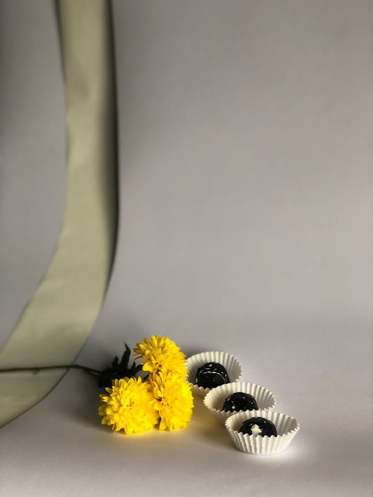 A simple and elegant composition featuring yellow flowers and chocolates in a minimalist style.