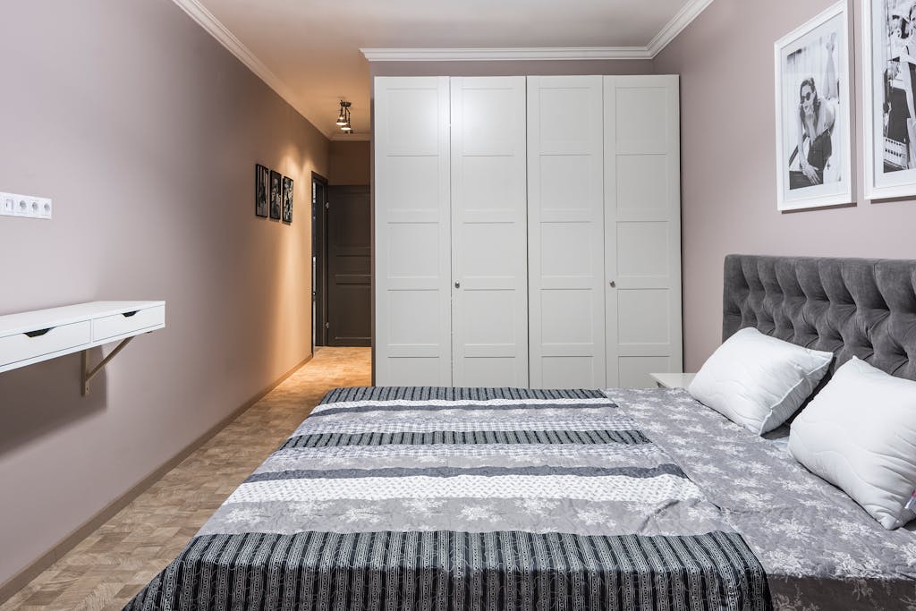 A sleek, modern bedroom featuring a bed, wardrobes, and wall decorations.