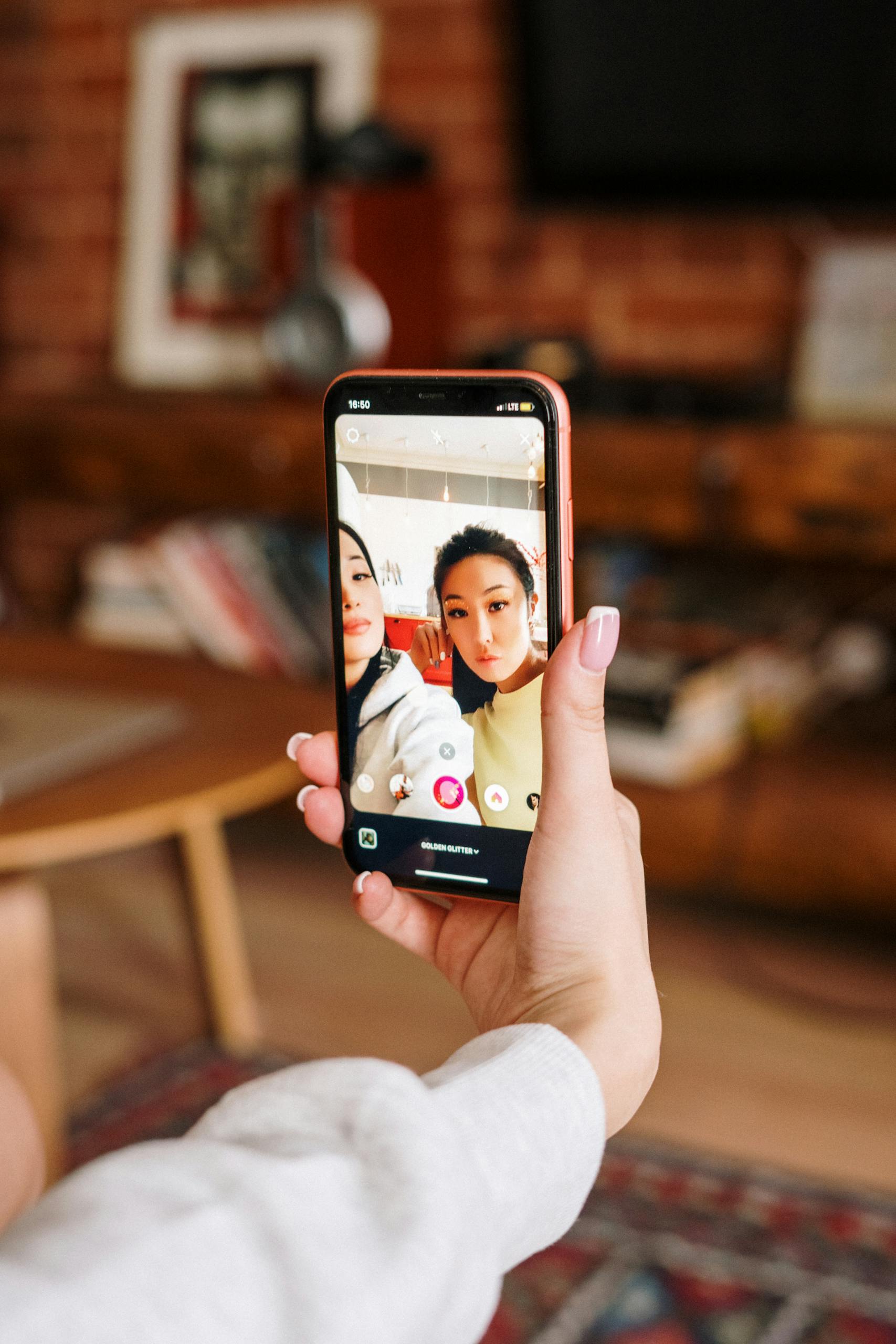 A snapshot of two friends capturing a selfie indoors, highlighting friendship and technology in a cozy home setting.