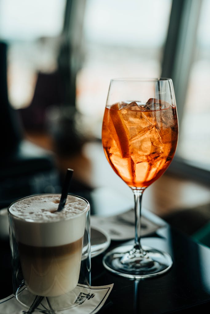A stylish café table with a refreshing iced cocktail and frothy coffee, perfect for leisure moments.