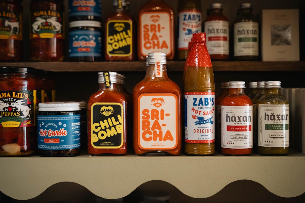 A variety of hot sauces and spices neatly arranged on a store shelf, showcasing diverse flavors.