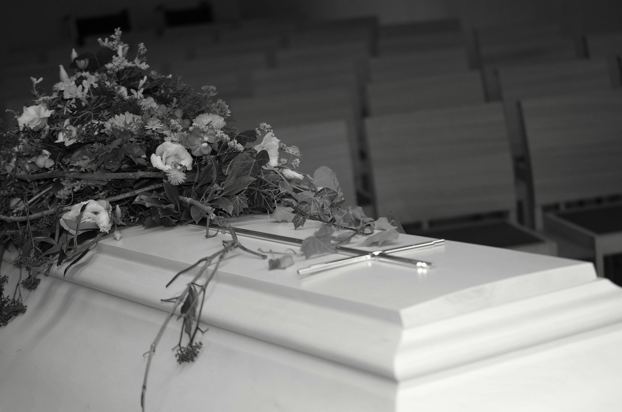 A white casket adorned with flowers inside a serene chapel, evoking calm and reflection.