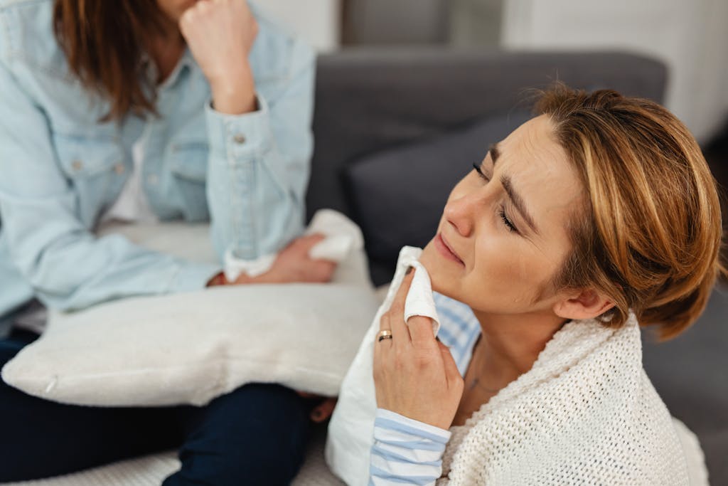 A woman crying with a napkin, comforted by a friend, expressing emotions.
