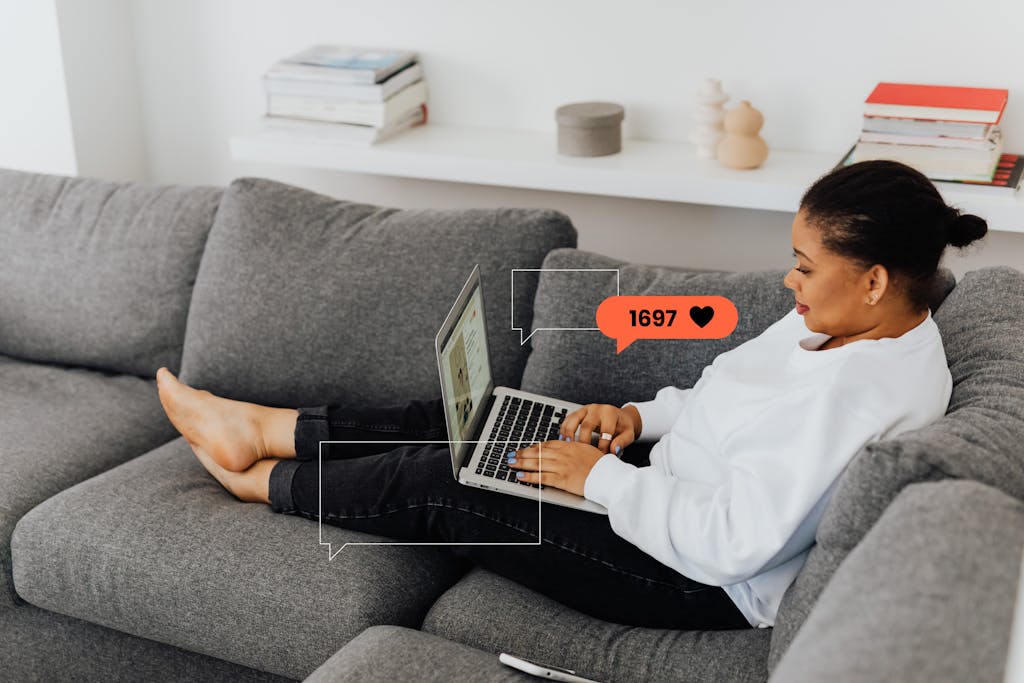 A woman enjoys working from home on her laptop, comfortably seated on a sofa.