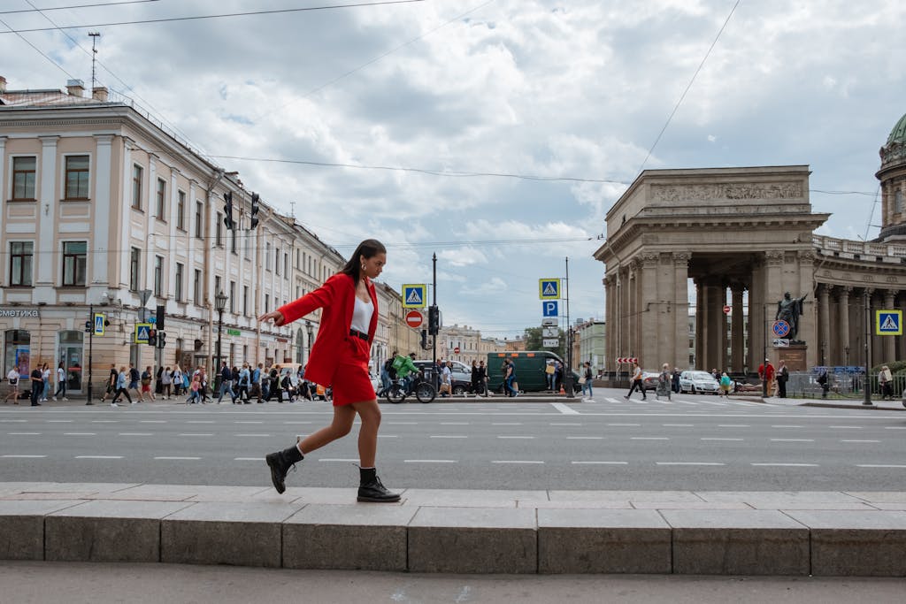 A woman in a fashionable red suit walks near the Kazan Cathedral in Saint Petersburg, Russia.