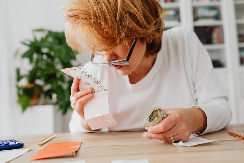 A woman sitting at a desk, reviewing bills and cash, symbolizing financial planning and management.