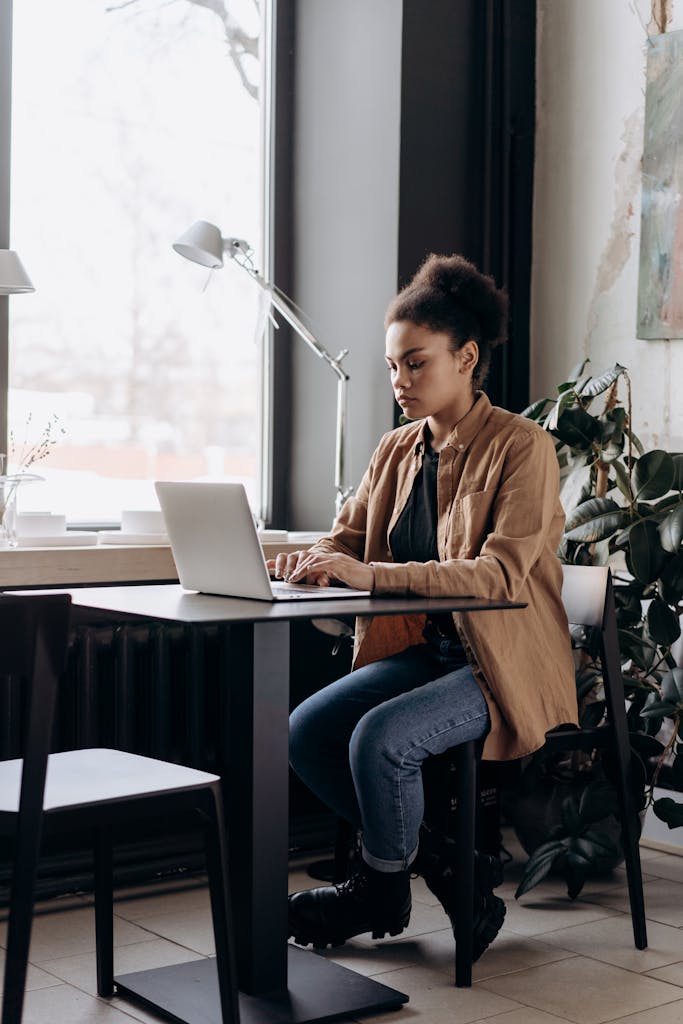 African American woman working on a laptop in a modern office setting.