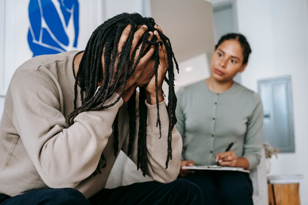 Anonymous frustrated African American male touching head near serious female partner with clipboard while interacting in room