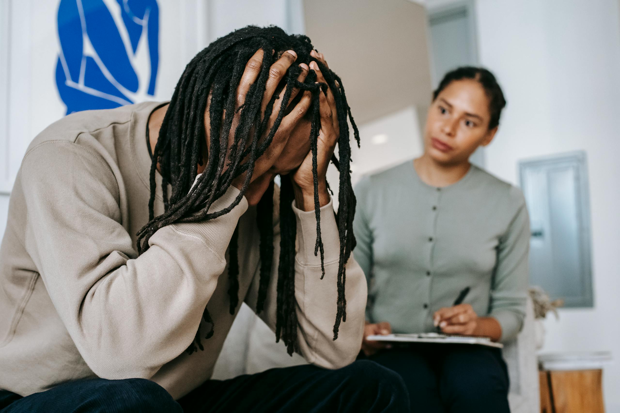 Anonymous frustrated African American male touching head near serious female partner with clipboard while interacting in room