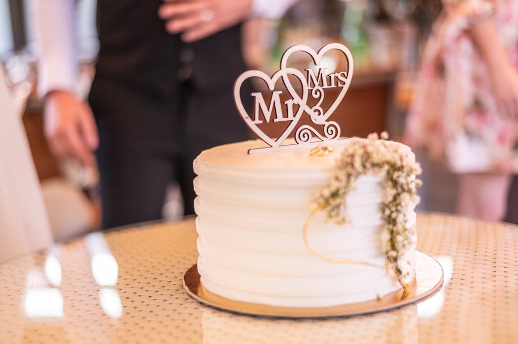 Beautiful white wedding cake adorned with a 'Mr & Mrs' topper and floral embellishments.