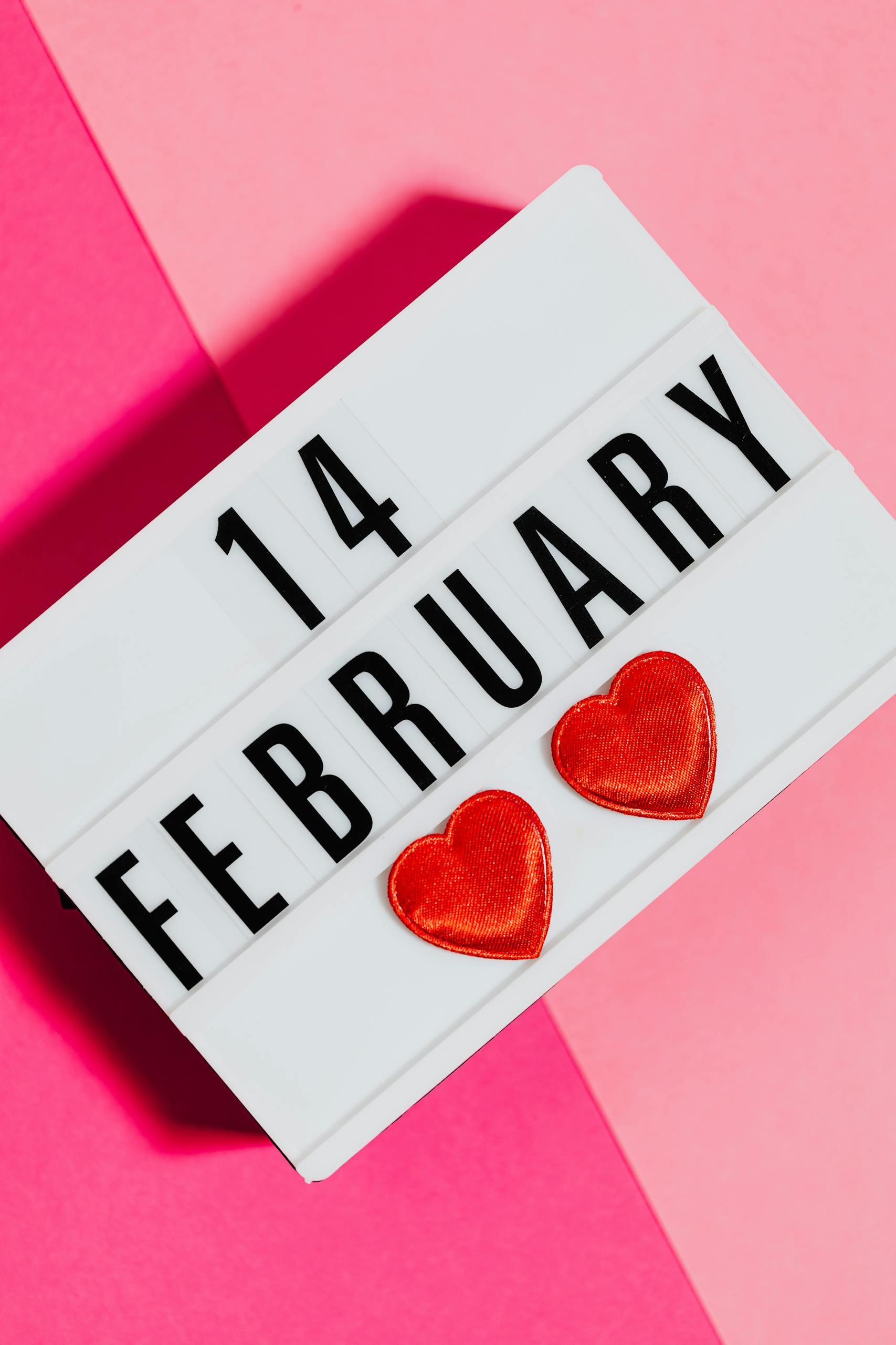 Bright Valentine's Day sign with hearts on a vibrant pink background, perfect for February 14 celebrations.