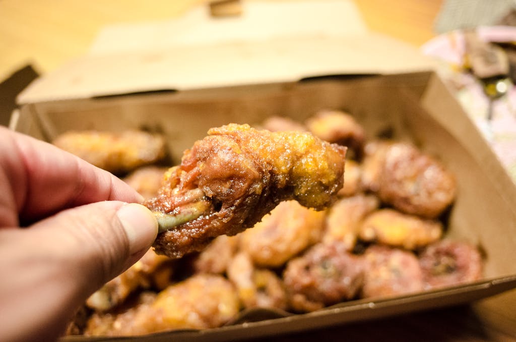 Close-up of a crispy fried chicken drumstick held in hand, ready to enjoy.