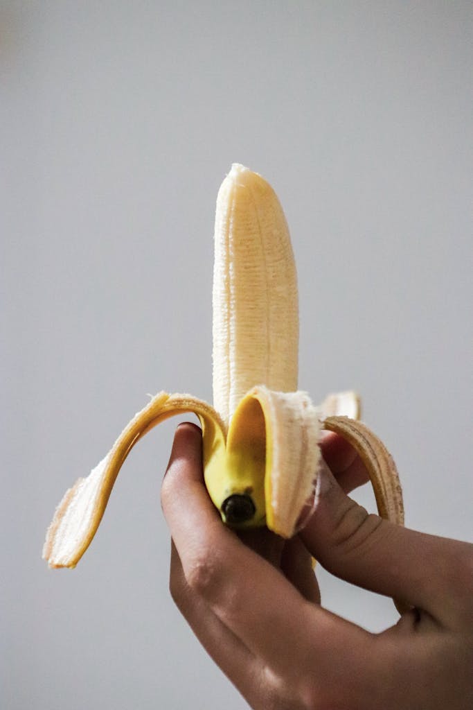 Close-up of a hand peeling a fresh banana, showcasing texture and color.
