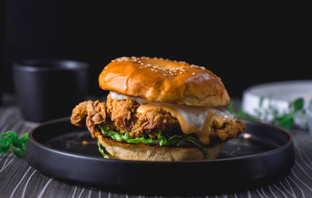 Close-up of a mouth-watering crispy chicken sandwich on a dark background.