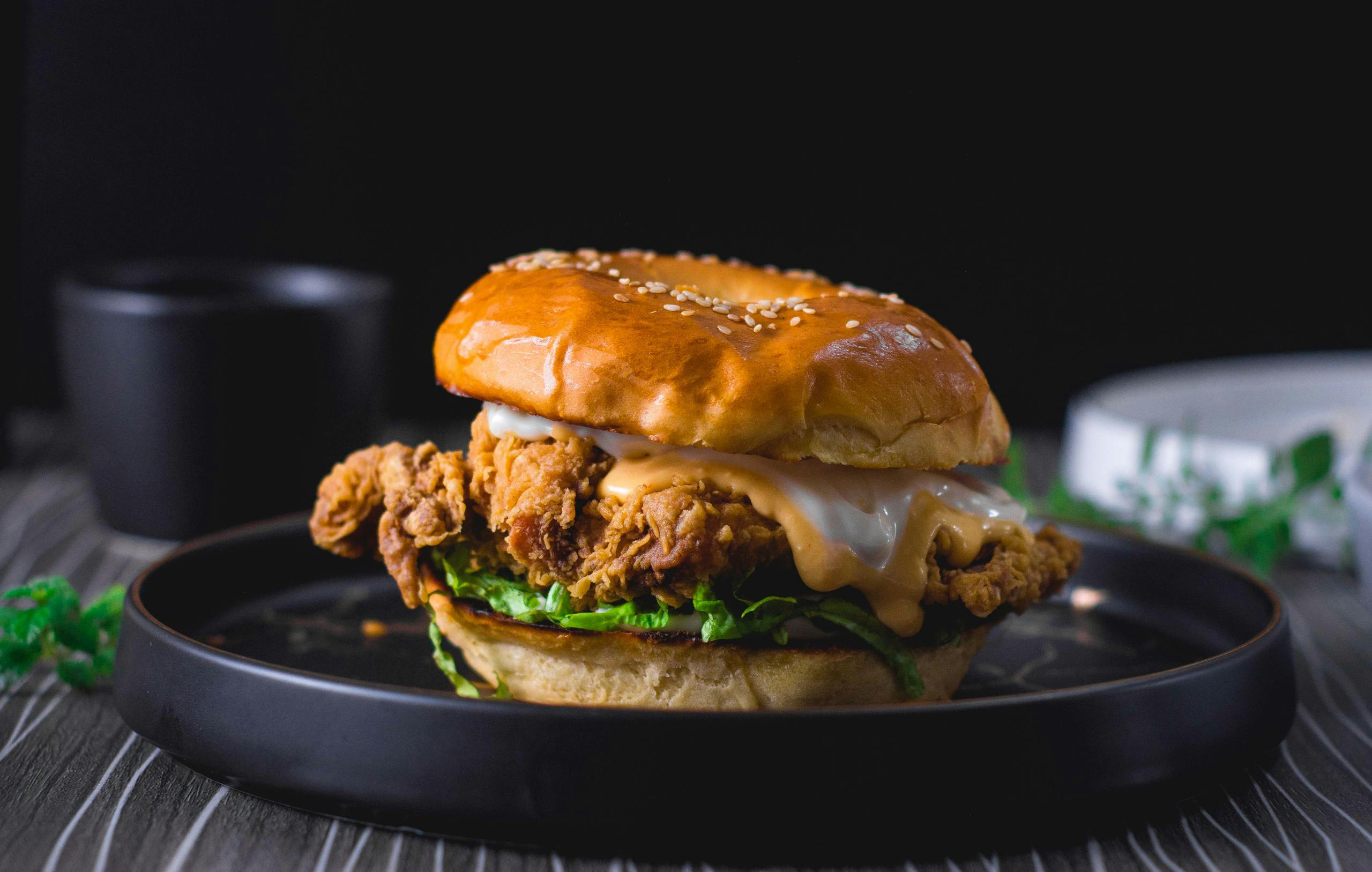 Close-up of a mouth-watering crispy chicken sandwich on a dark background.
