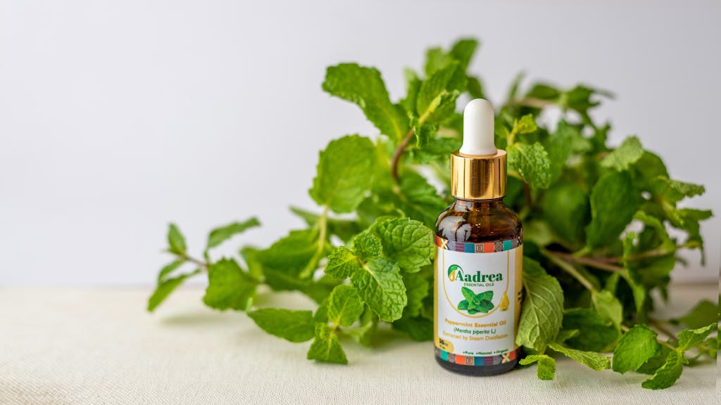 Close-up of a peppermint essential oil bottle surrounded by fresh mint leaves, perfect for natural wellness use.