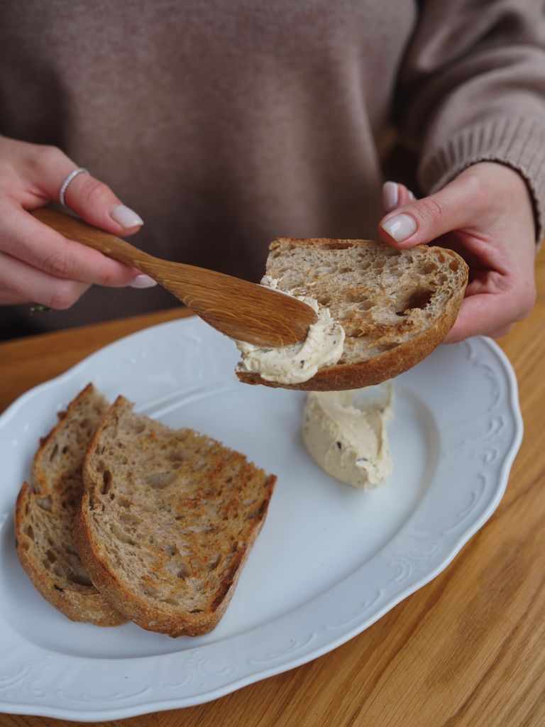 Close-up of a person spreading butter on wholemeal bread for a healthy breakfast.