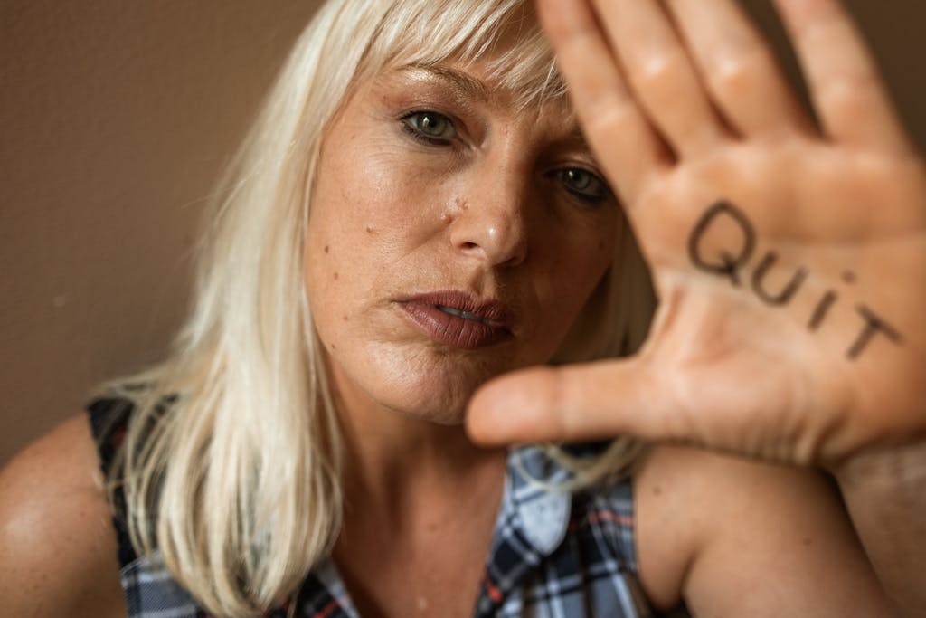 Close-up of a woman with 'Quit' written on her hand, expressing determination.