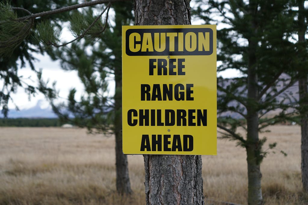 Close-up of caution sign on tree trunk in New Zealand rural area, highlighting humor.