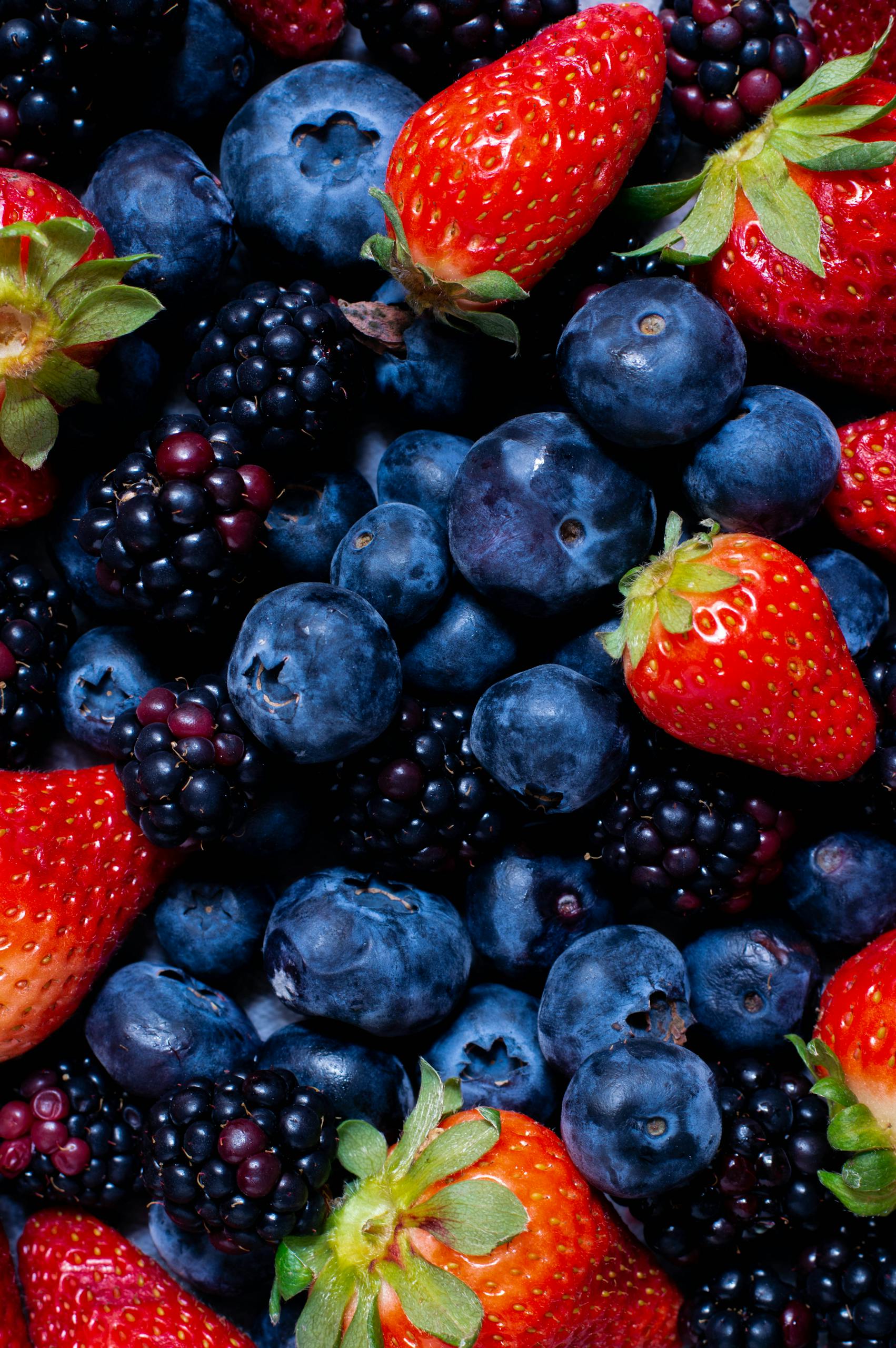 Close-up of fresh strawberries, blueberries, and blackberries, a healthy fruit mix.
