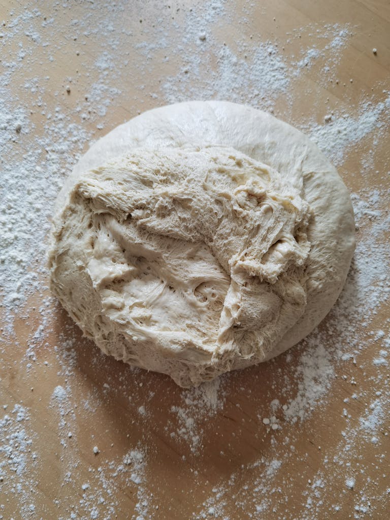 Close-up of freshly kneaded bread dough resting on a floured wooden surface.