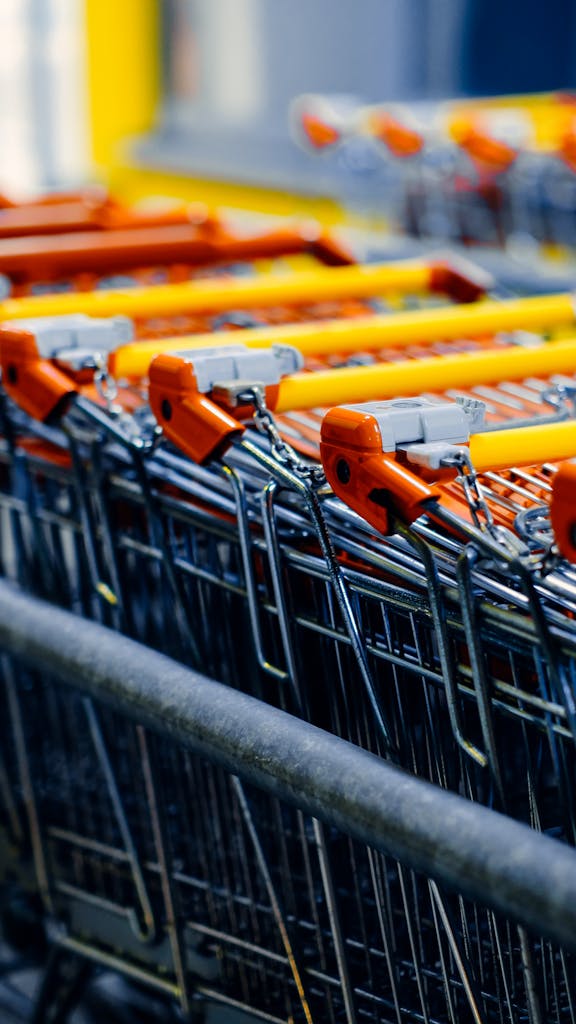 Close-up of orange-handled shopping carts lined up in a store aisle.