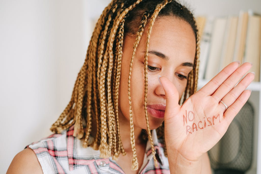 Close-up portrait of a woman with 'No Racism' written on hand, promoting anti-racism message.