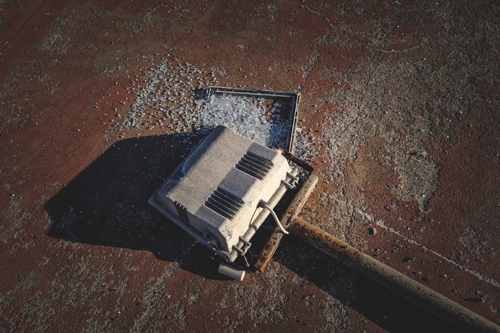 Close-up shot of a broken streetlight laying on a rough, textured surface. Ideal for urban decay themes.