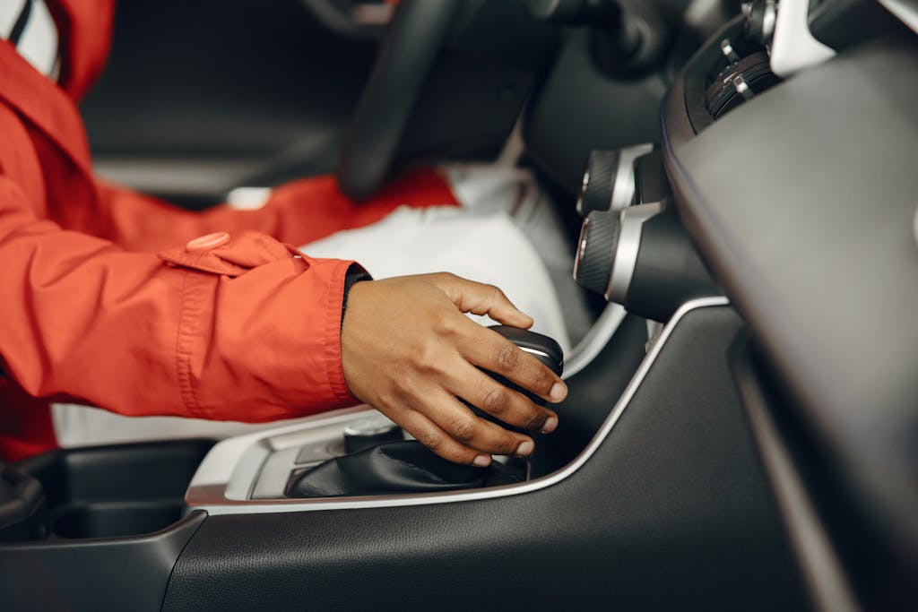 Close-up view of a person shifting gears in a car interior, illustrating driving expertise.