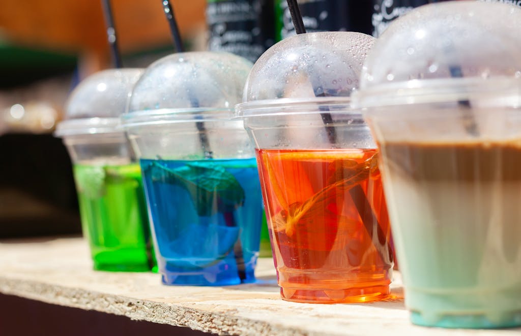 Colorful assortment of drinks in plastic cups with straws, perfect for refreshing summer days.