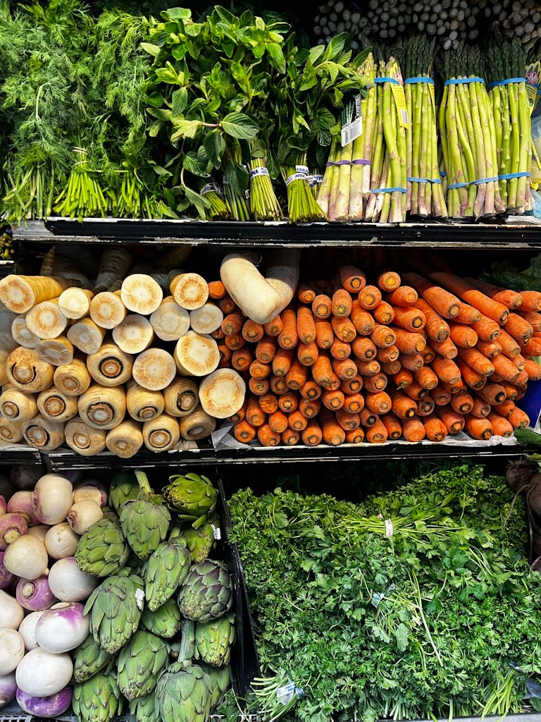 Colorful assortment of fresh vegetables including asparagus, carrots, and herbs in a grocery store display.