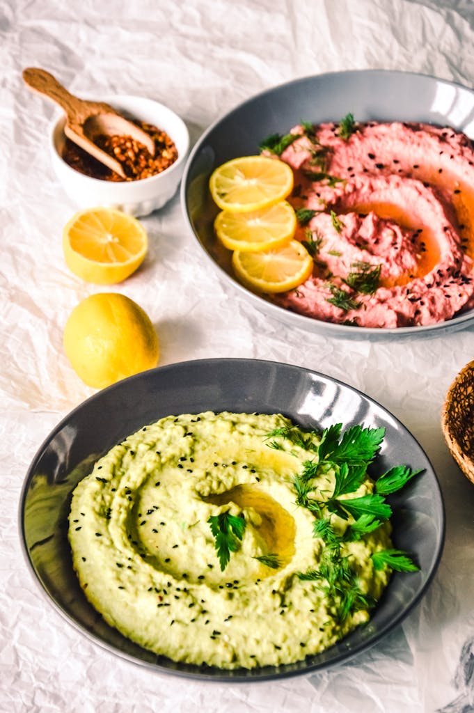 Colorful bowls of hummus with fresh garnishes, showcasing a vibrant and healthy meal.