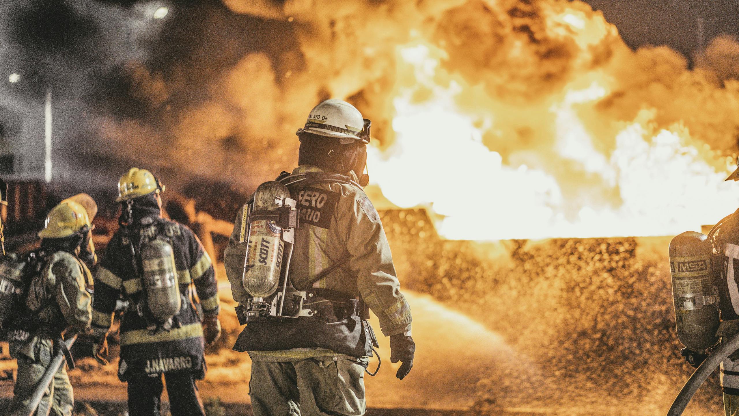 Courageous firefighters actively combat a massive fire, showcasing bravery and teamwork at night.