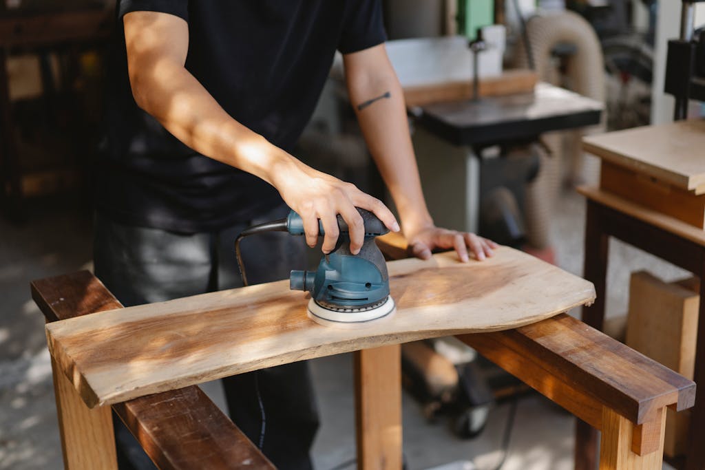 Crop anonymous craftsman using manual sander for polishing wooden plank for creating woodwork
