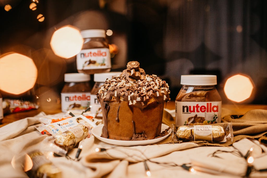 Decadent chocolate cake with Nutella jars and assorted candies on a warm, indulgent display.