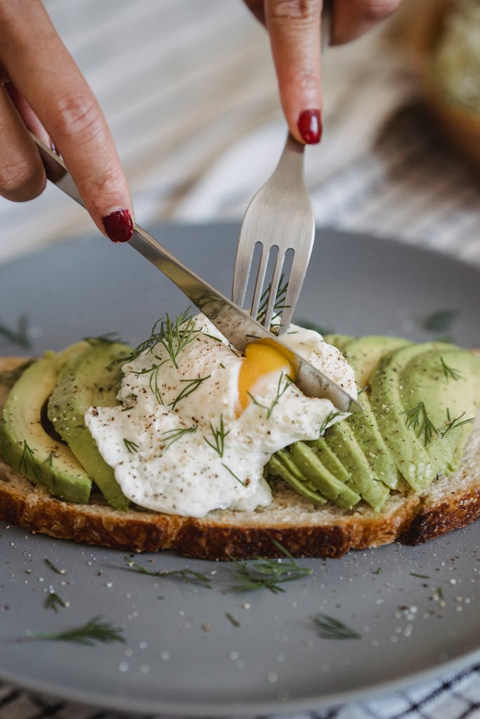 Delicious avocado toast topped with a perfectly poached egg and fresh herbs, ideal for a healthy meal.