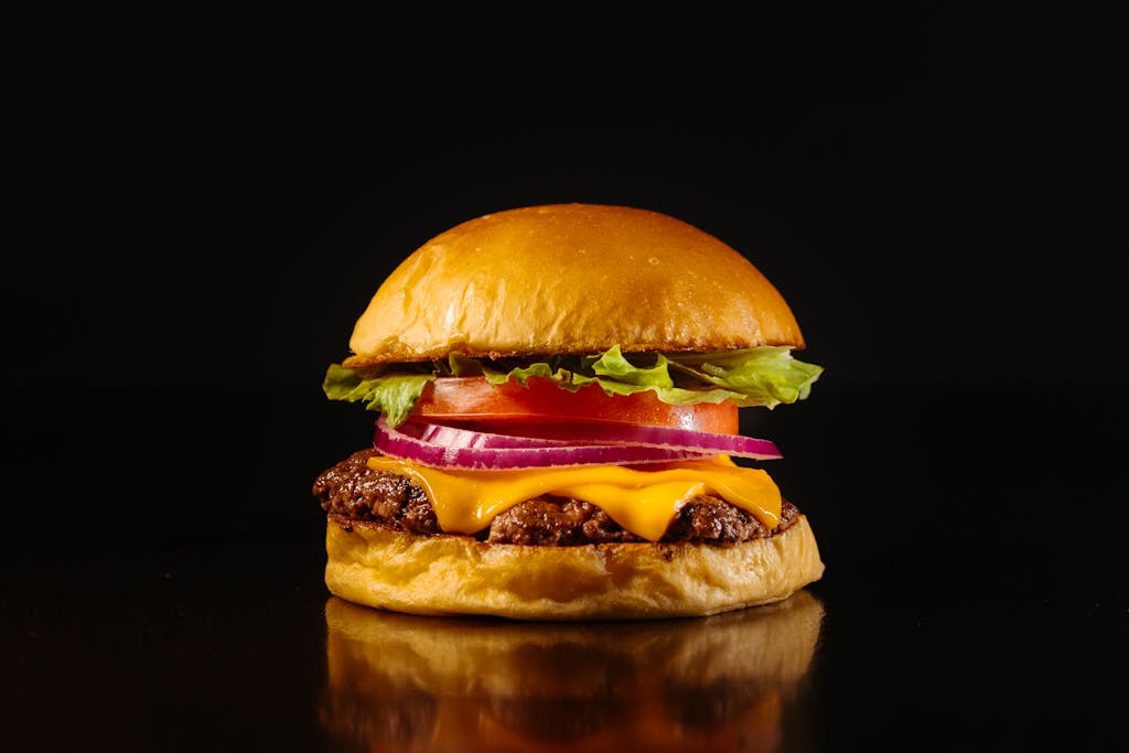 Delicious cheeseburger with fresh ingredients on a dark background, perfect for food lovers.