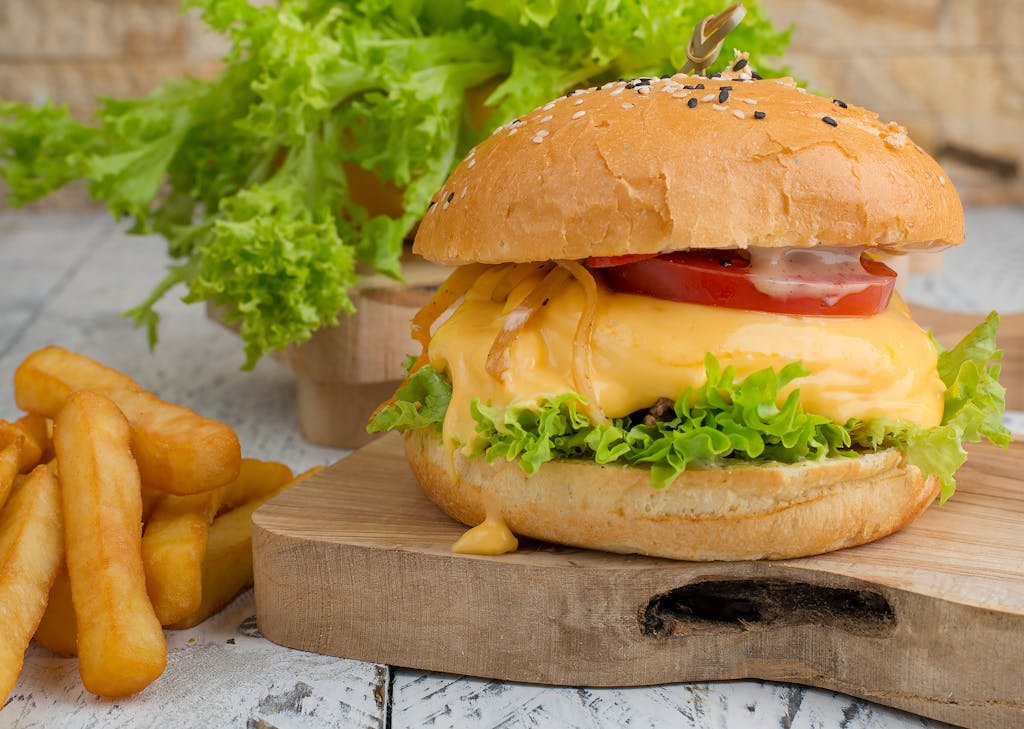Delicious cheeseburger with fresh lettuce and crispy fries on a wooden board.