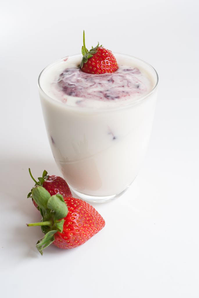 Delicious strawberry yogurt dessert served in a glass with fresh strawberries on a white background.
