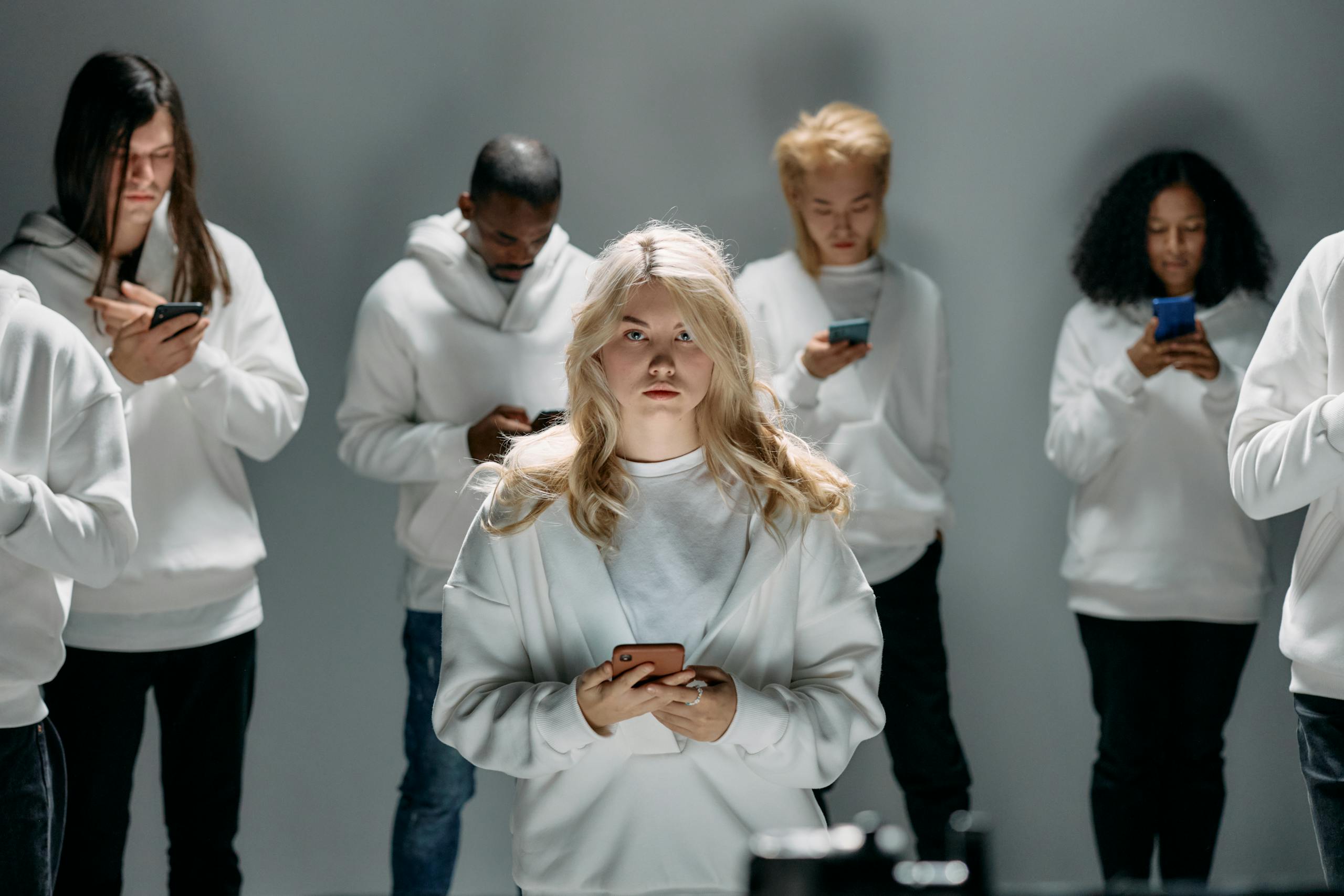 Diverse group of individuals engaging with smartphones, symbolizing modern digital connection and technology.