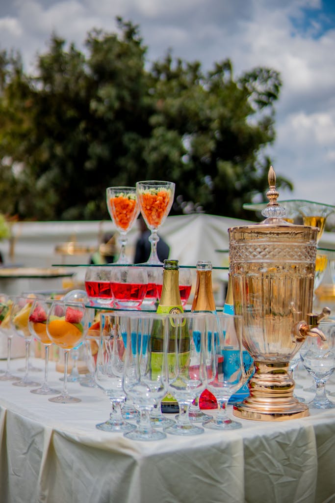 Elegant outdoor dining setup with various drinks, fruit garnishes, and decorative drinkware.