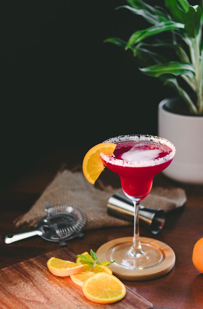 Elegant red cocktail with orange slice garnish on a table, perfect for a stylish bar scene.