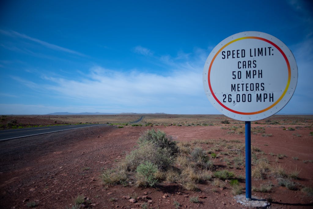 Funny speed limit sign in the Arizona desert, highlighting cars and meteor speeds.